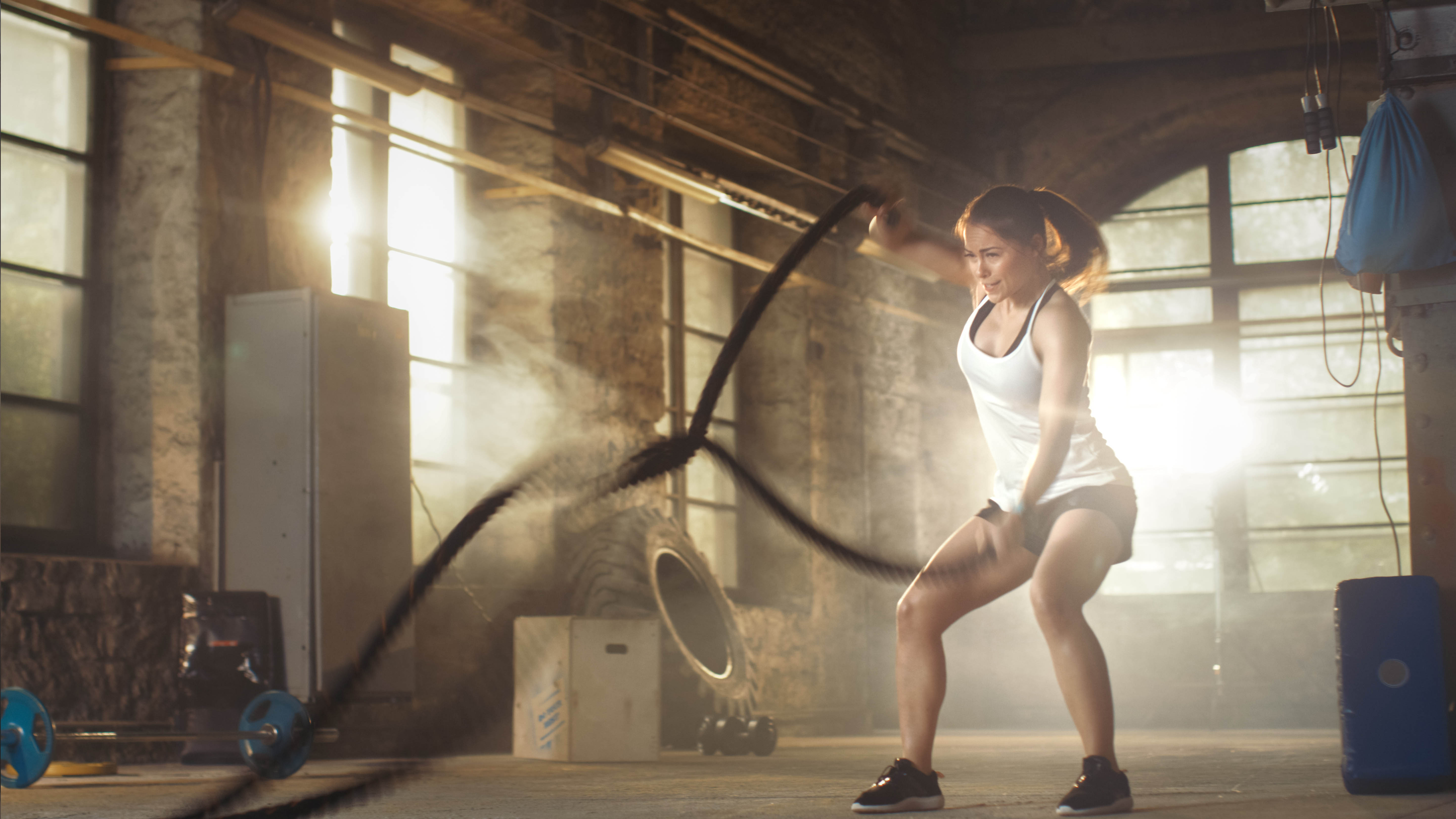 Strong, fit woman using the battle ropes for a workout in a gym